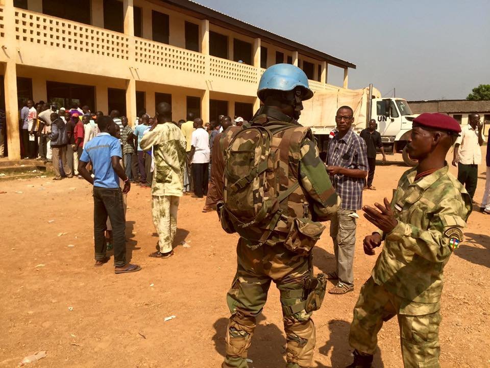 A peacekeeper confers with local security forces outside a school in Bangui, Central African Republic