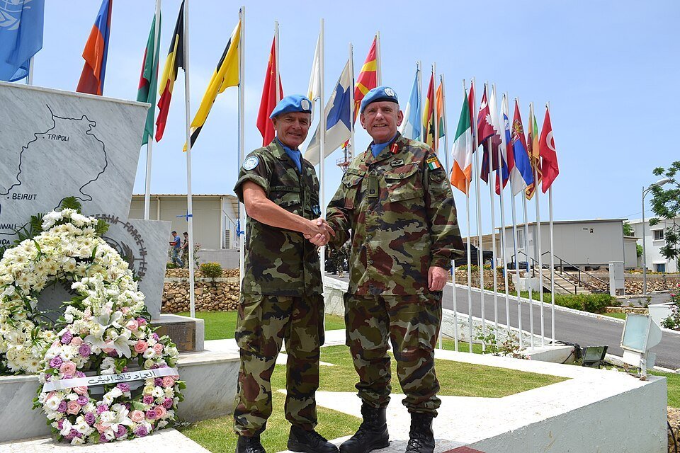 UNIFIL commanders shake hands beside a memorial wreath and contributing-nation flags